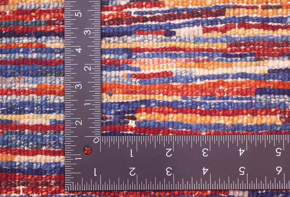 Close-up of the hand-knotted back of a modern Stripy Gabbeh rug with red, blue, orange, and cream bands, shown with a dark metal L-shaped ruler to show scale of the knot density.