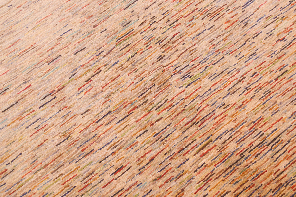 A close-up of a textured Afghan Gabbeh carpet with a warm beige base and dense, diagonal multicolour flecks in orange, red, blue, green, and brown.