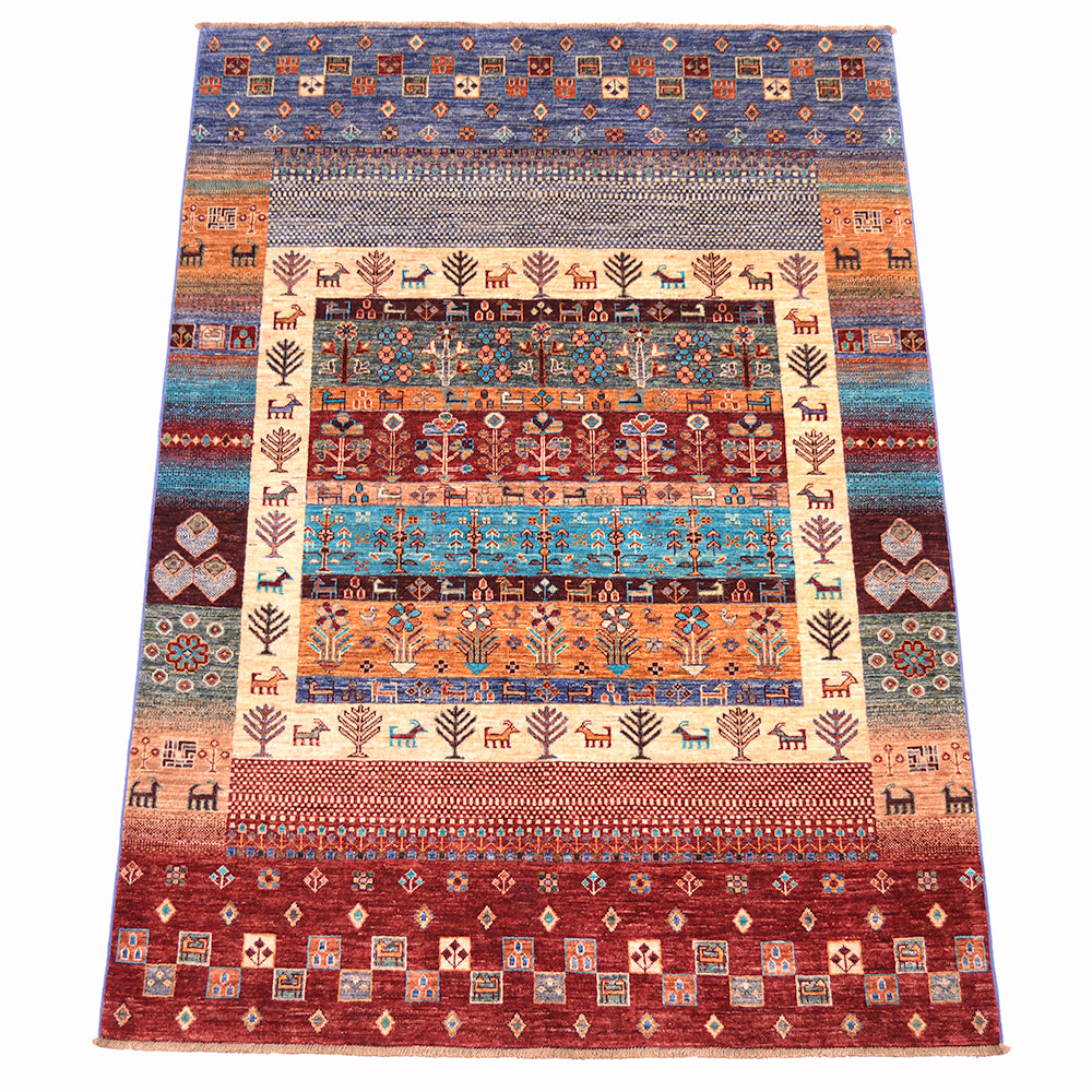 A 7x5 rectangular hand-woven multicolour Loribaft area rug with a complex geometric and animal motif, featuring a central cream panel surrounded by bands of blue, orange, red, and brown patterns with stylised deer /goats and trees.