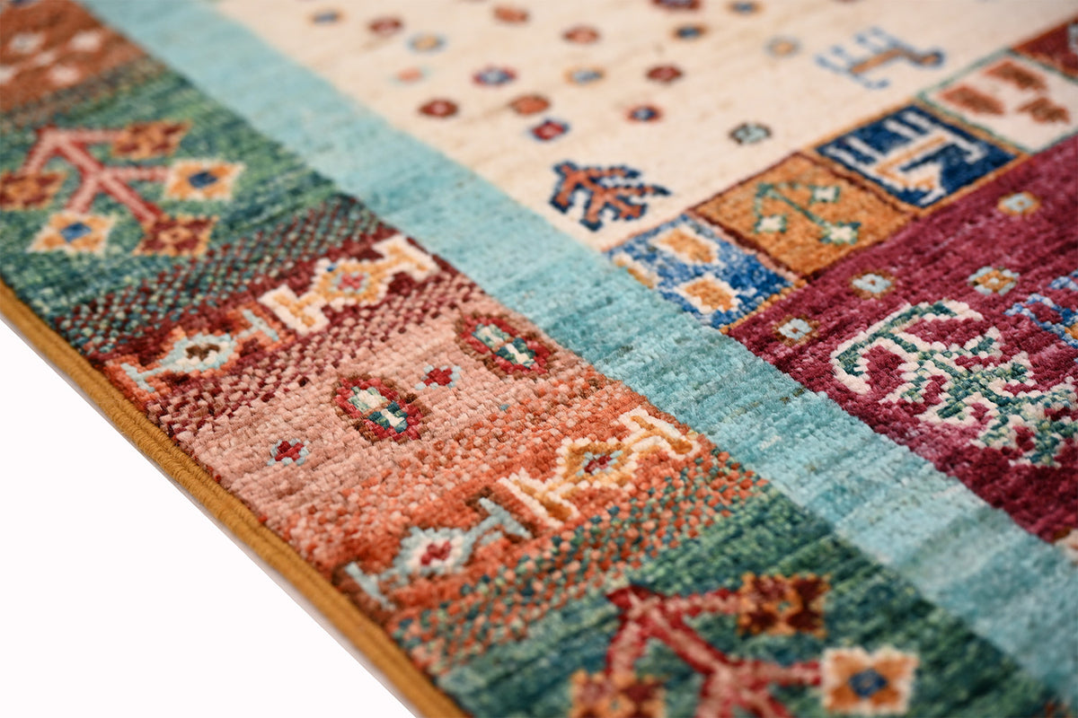 Afghan Loribaft Gabbeh handmade rug side detail, multicolour motifs on textured field with mustard selvedge edging.