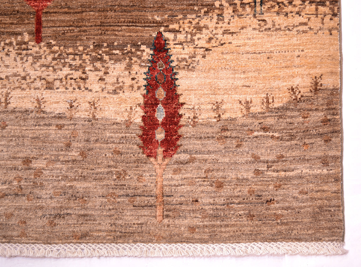 A close-up of a corner of a Pictorial hand-knotted Loribaft carpet showing a textured beige and brown field with a central red tree-like motif and a white fringed edge along the bottom.