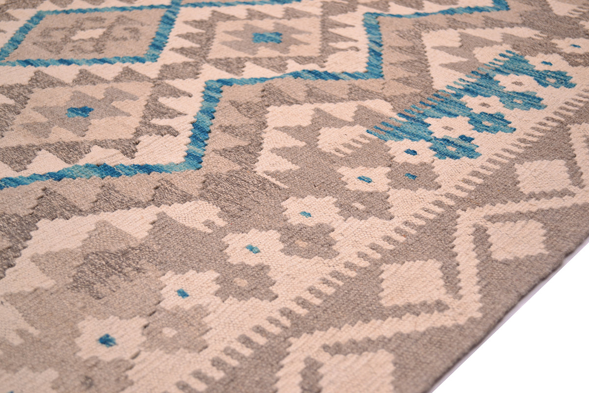 Close-up of a handwoven patterned Kilim Afghan area rug with a geometric and tribal-inspired design in beige, taupe, and bright blue.