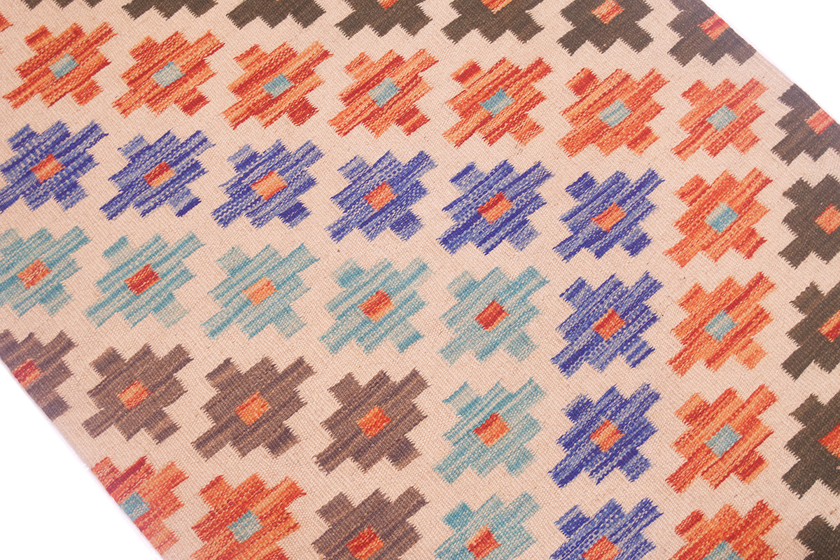 A close-up of a woven Kilim hallway runner with a repeating geometric pattern in orange, blue, light blue, brown, and dark brown on a warm beige background.