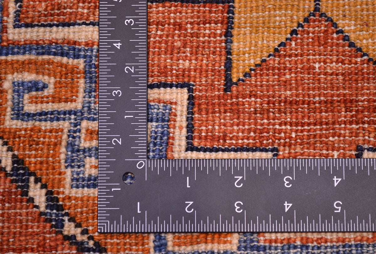 Detailed view of Afghan carpet showing back of knots and fine knotting. Goldren ochres colours, rust reds, creams and blues.