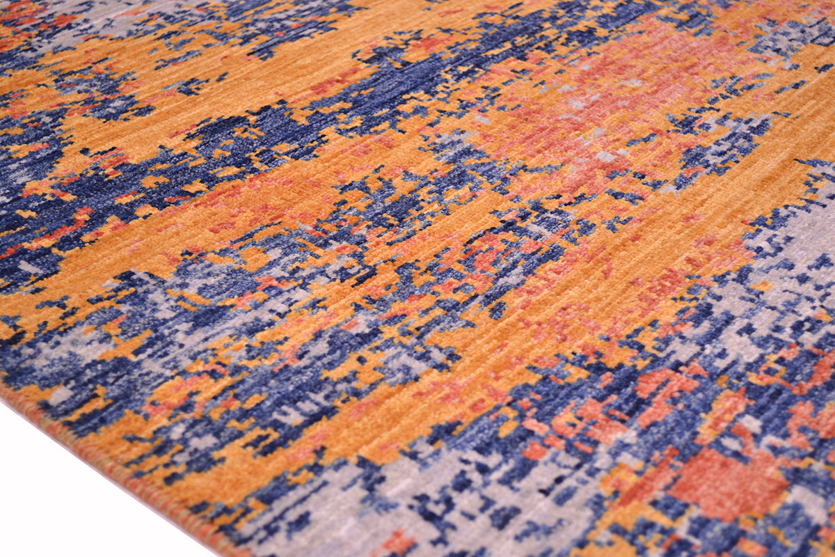 Detail of side of borderless design abstract rug with blue, grey coral and light amber wool pile and abstract modern design.
