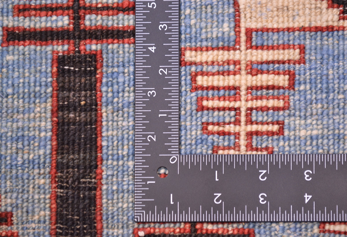 Close-up of a the hand-knotted back of a blue Aryana long runner with a dark metal ruler placed vertically and horizontally to show scale of the knot density, featuring a blue, red, and beige geometric design.