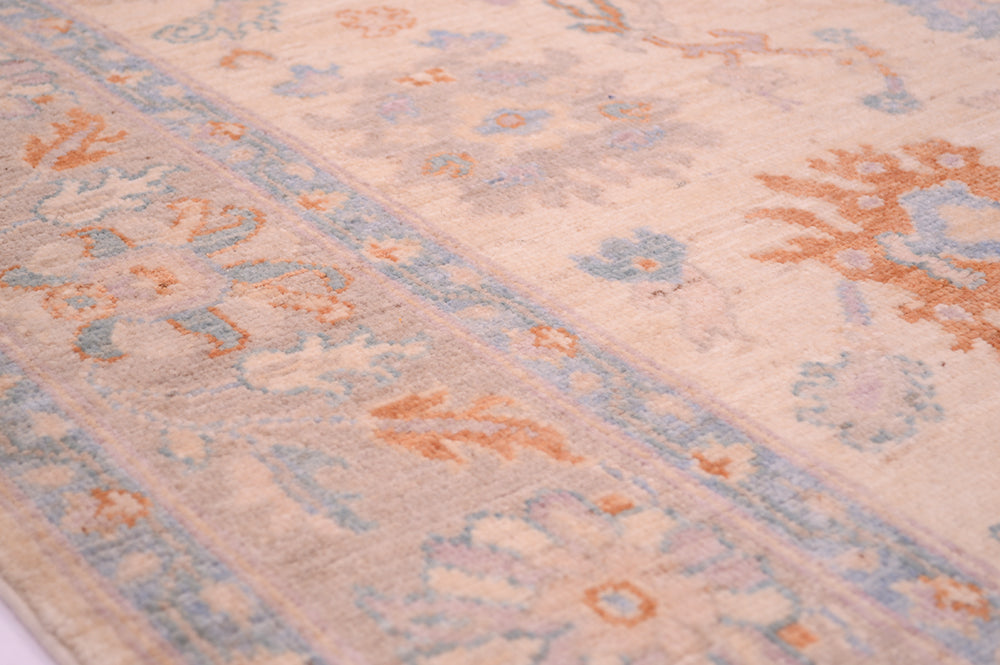 Detail of floral border in soft hues of terracotta and blue of Afghan Ushak carpet.
