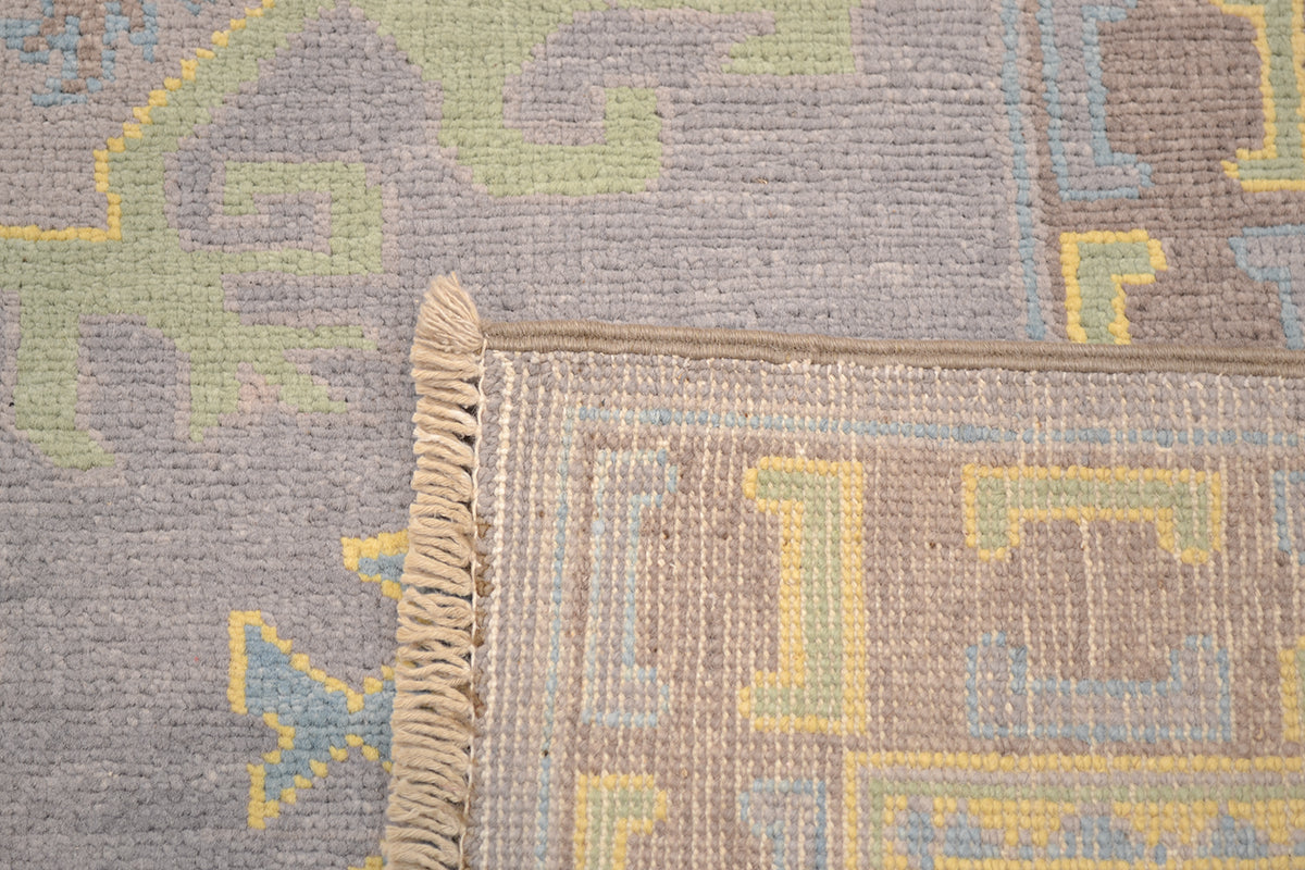 Corner fringe detail on grey Oushak carpet with yellow and blue pattern accents