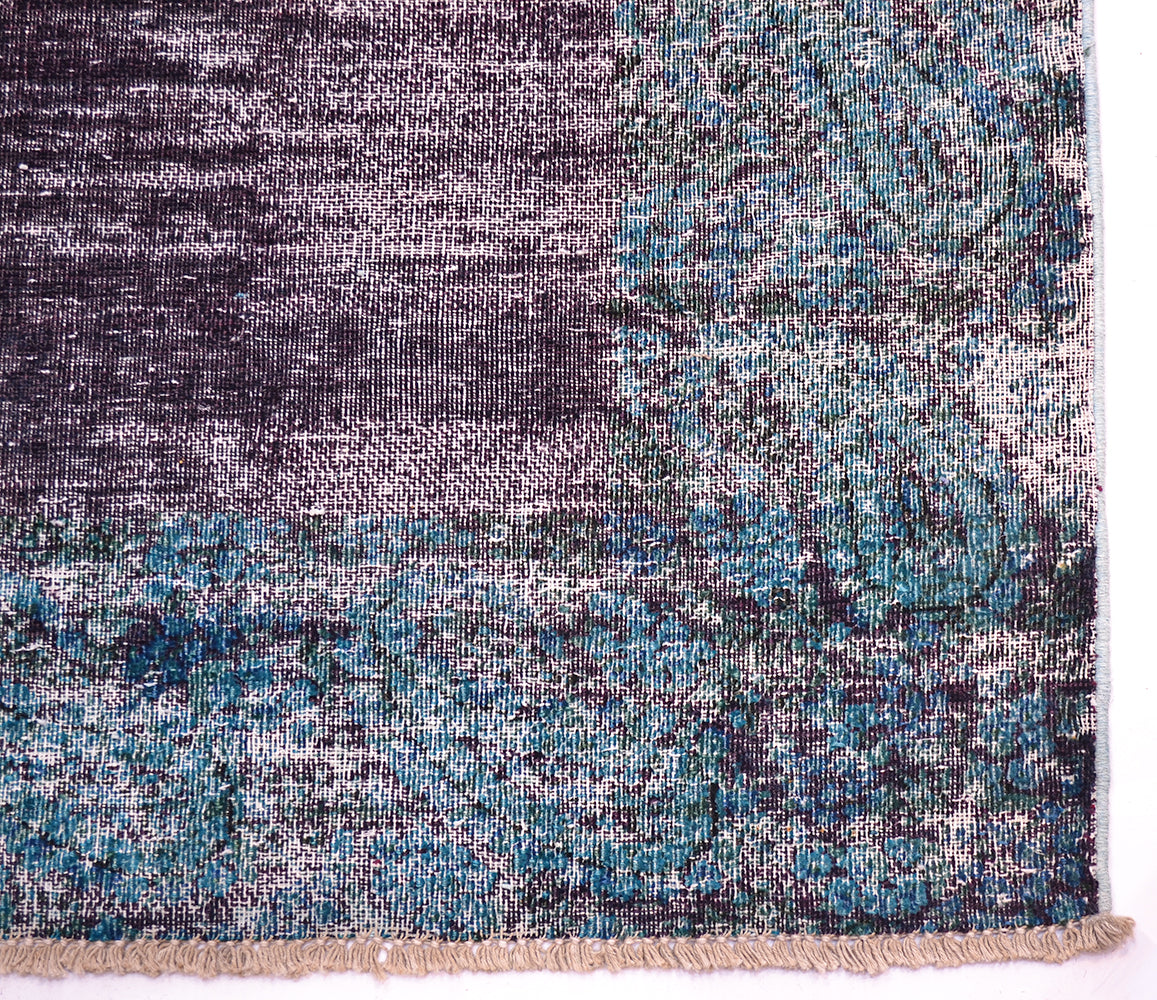 Corner detail of hallway vintage runner in aubergine and pertrol blues. Plain field colour of deep purple-aubergine with border in teal green blue with taditonal boteh design. Cotton warp fringes,