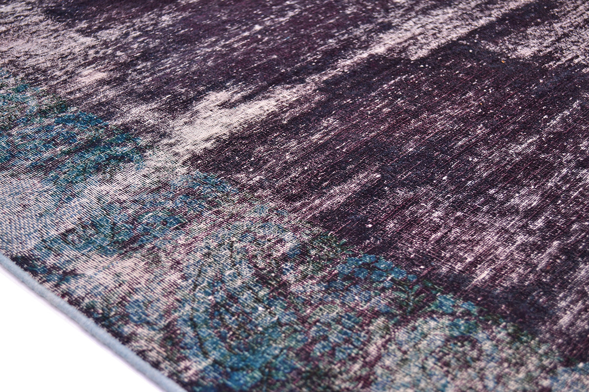 Close up detail of vintage overed dyed carpet showing main field of deep purpled indigo /aubergine with detail of border with floral paisley boteh in peacock teal greens and petrol blues. Inky blue teal.