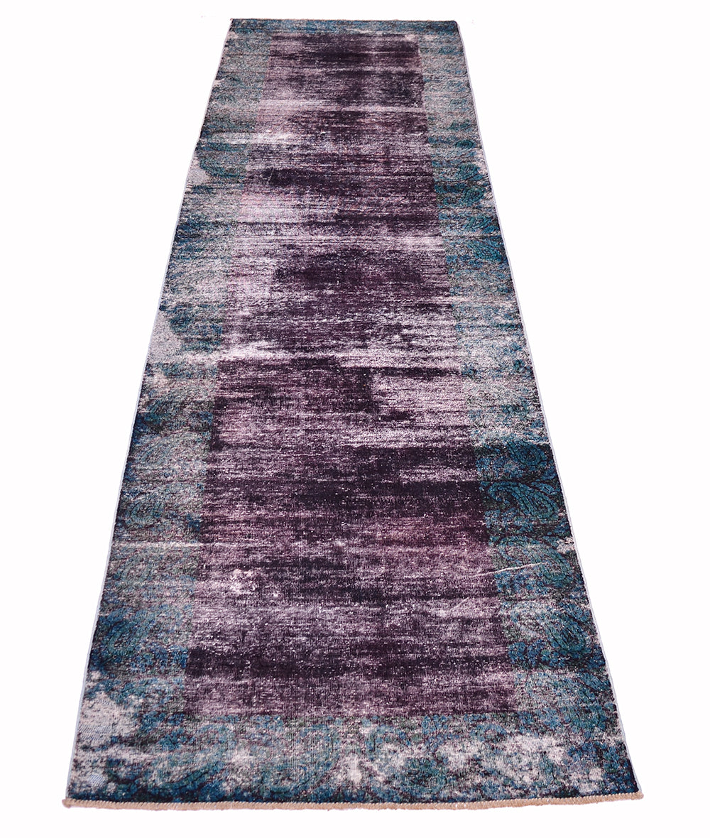 Overall view of vintage overdeyed carpe with ages distressed pile with deep aubergine coloured main centre field and border with deep blue-green teal traditional boteh and floral-paisley patterning. High and low pile.