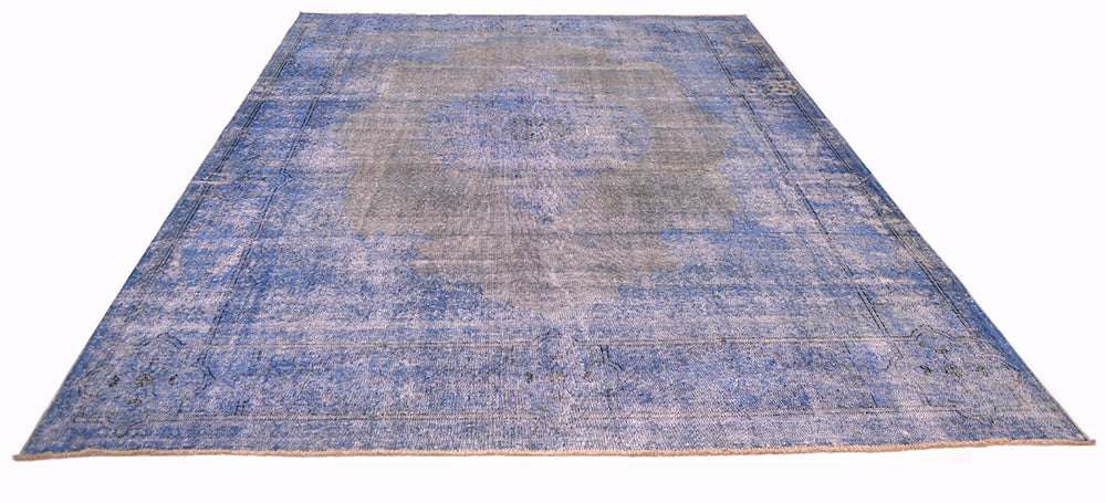 View of vintage overdyed carpet in blue tones and greys. Traditional format with medallion design and variery of blue tones. Soft grey totanlies and shaven, zero pile.