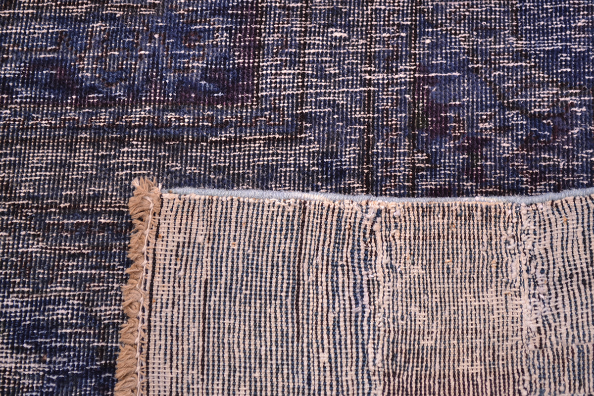 Back of handmade and hadnknotted carpet showing cotton warps and wefts and back of knots. Deep blue indigo pile with low cut pile.
