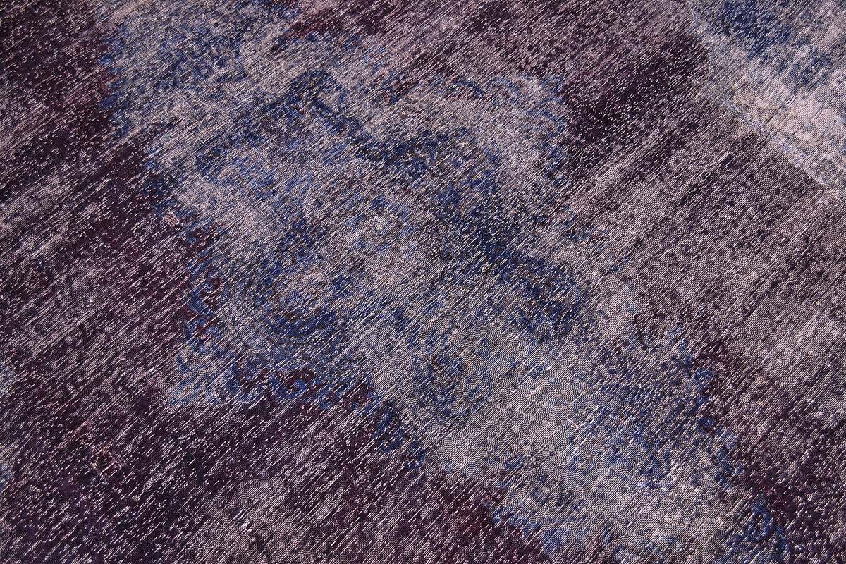 Close up and detail of main field and centralised motif of large vintage carpet with richly saturated tones of indigo and aubergine colouration. Handknotted with zero pile amd cotton warp foaundation. Overdyed vintage carpet with traditional design.