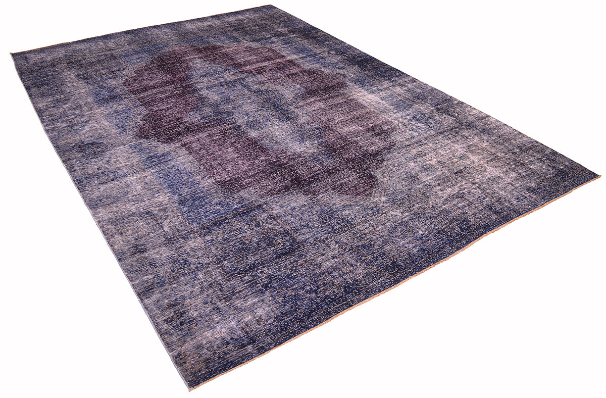 Angled view of Blue and deep teal blue- like tones vintage carpet with centralised motif in aubergine. Rich colouration and fine knotting. Shaved zero pile with sturdy cotton foundation. Classic design with modern colours.