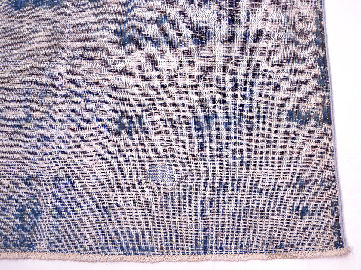 Detail of corner of overdyed carpet in blue and magenta fushia showing warp cotton threads and shaved distressed pile. Cotton warp foundation threads visible with cotton warp fringes. Areas of blue short pile in cobalt deep blue.