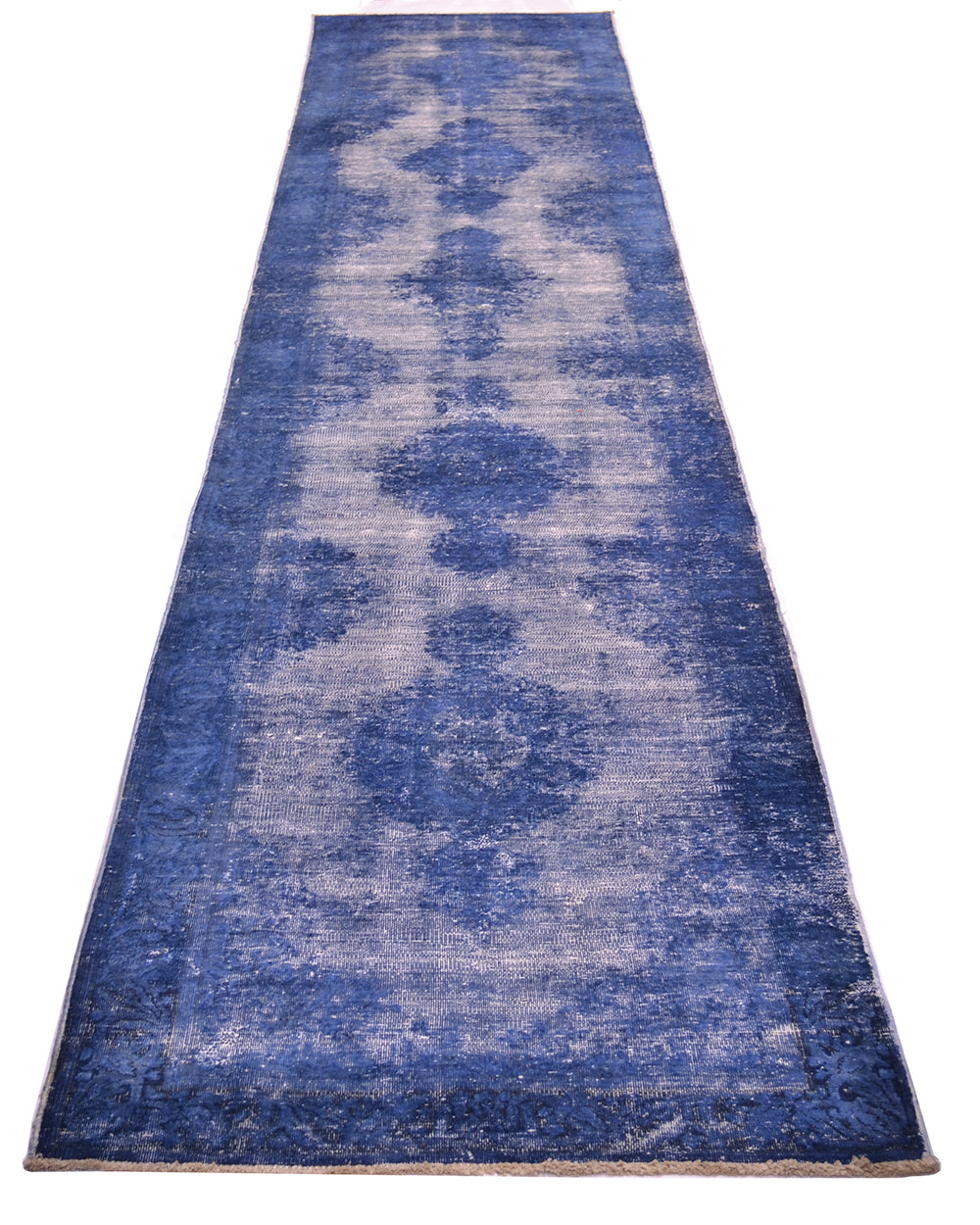 A long rectangular runner rug with a distressed, faded damask pattern in shades of blue and off-white, shown flat against a white background.