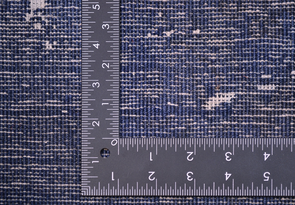Close-up of a blue and white textured runner/rug with a metal ruler to indicate scale.