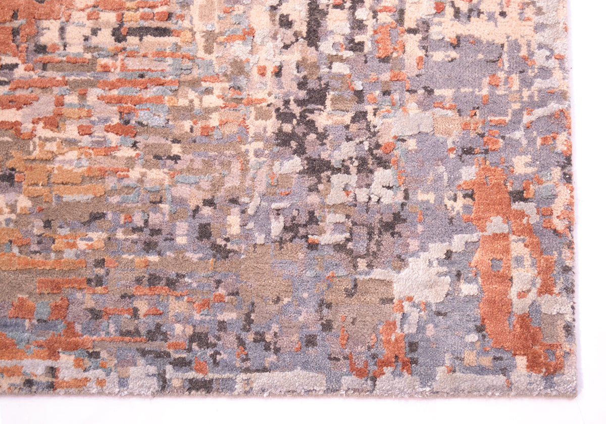 Corner view of handmade Indain carpet with blue greys and light bronze pile with raised silk highlights that are handcut. Cotton warp threads are bounds securely so no fringes visible.