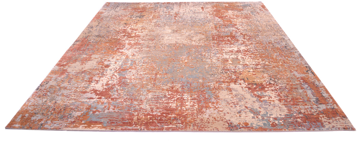Impressive overall view of abstract modern indian carpet with soft easrthy tonalities. Terracotta, golds, ligth teals and blues in raised silk as well as a background colour of stones and greys.