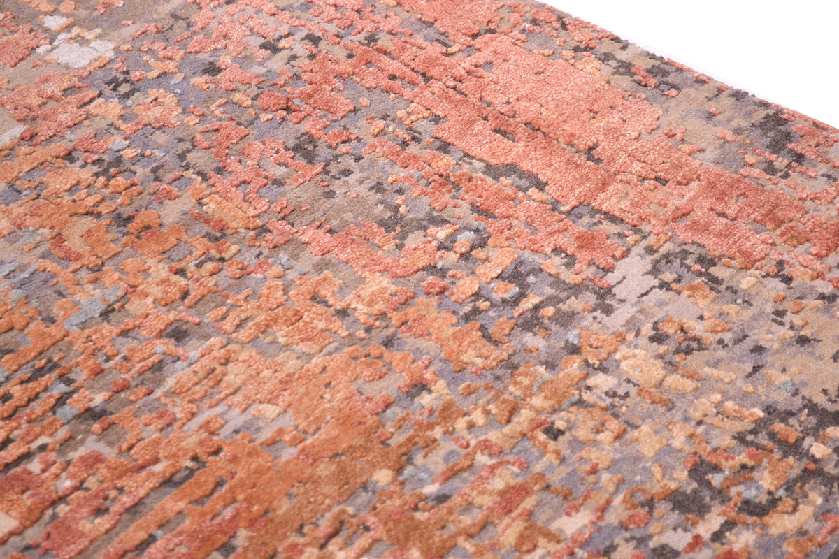 Close view of areas of raised silk in terracotta and light rust/ amber tones. The base ground wool pile with stone, taupe as well as pewter grey and hints of charcoal. Handknotted handmade carpet.