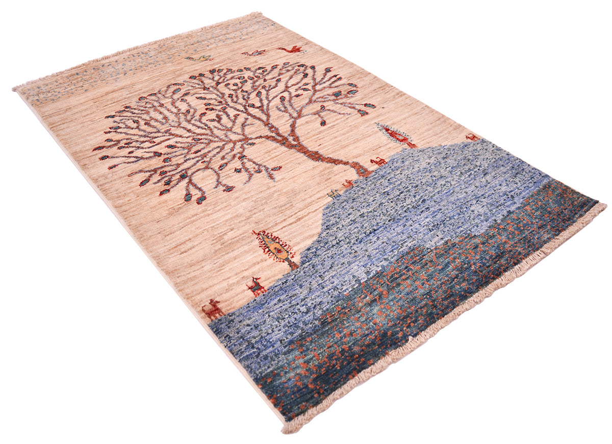 A rectangular Afghan Loribaft rug with a scenic landscape design, featuring a large tree on a beige background and a blue-toned coastal or mountainous scene with small red and orange details, shown on a plain white background.
