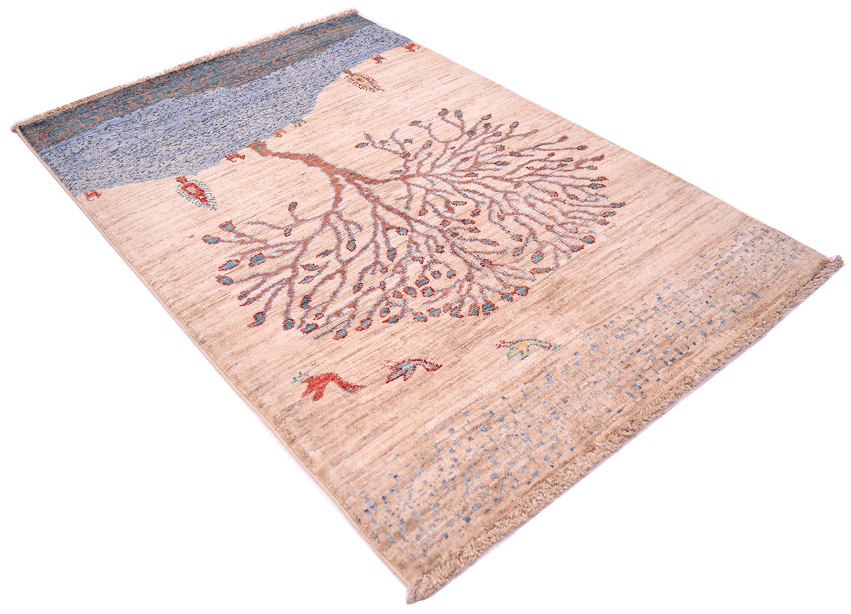 A rectangular Loribaft rug with a stylised tree design, featuring a beige centre, a blue patterned top section, and small bird motifs scattered across the surface.