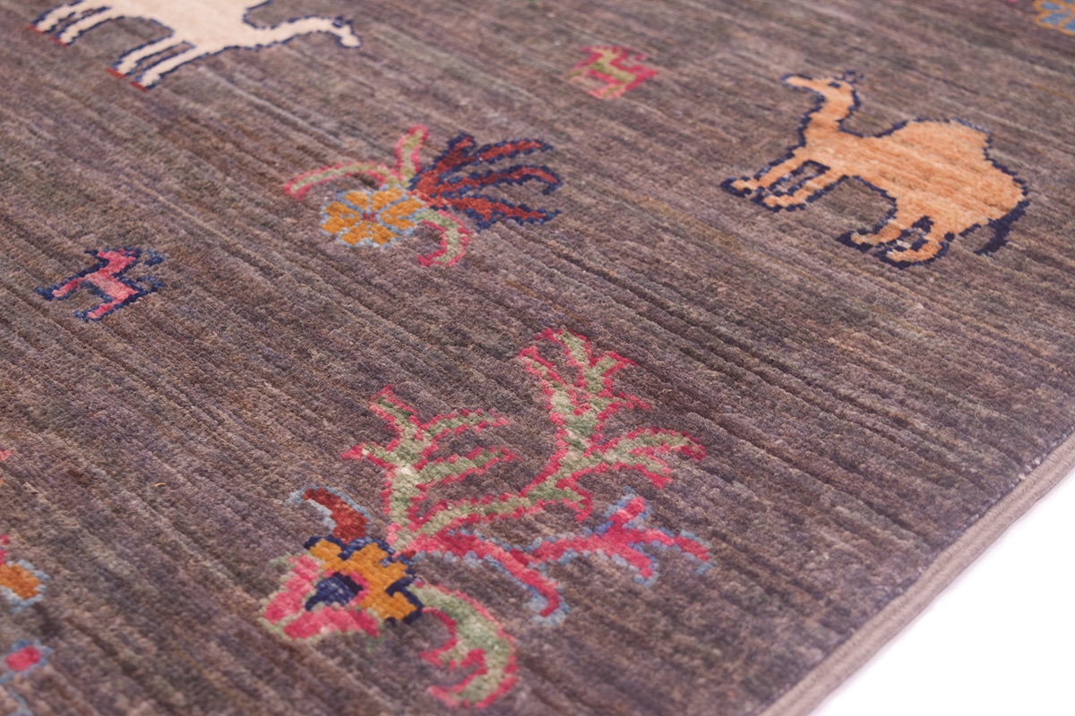A close-up of a textured grey-brown pictorial runner rug featuring hand-knotted stylised animal and floral motifs in muted pink, orange, blue, and cream.