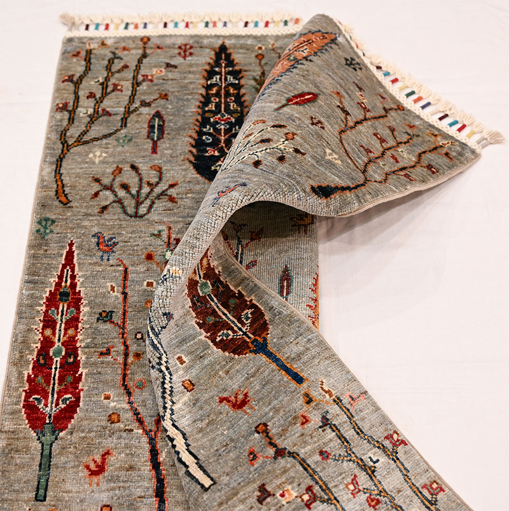 Afghan pictorial Loribaft rug in grey with tree motifs, patterned surface, and folded end showing dense weave