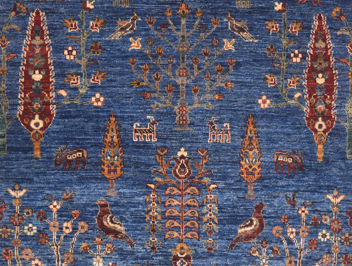 A close-up of a patterned pictorial Afghan Loribaft rug featuring a blue field with ornate motifs including birds, trees, floral elements, and small animal figures in rust, beige, and cream tones.