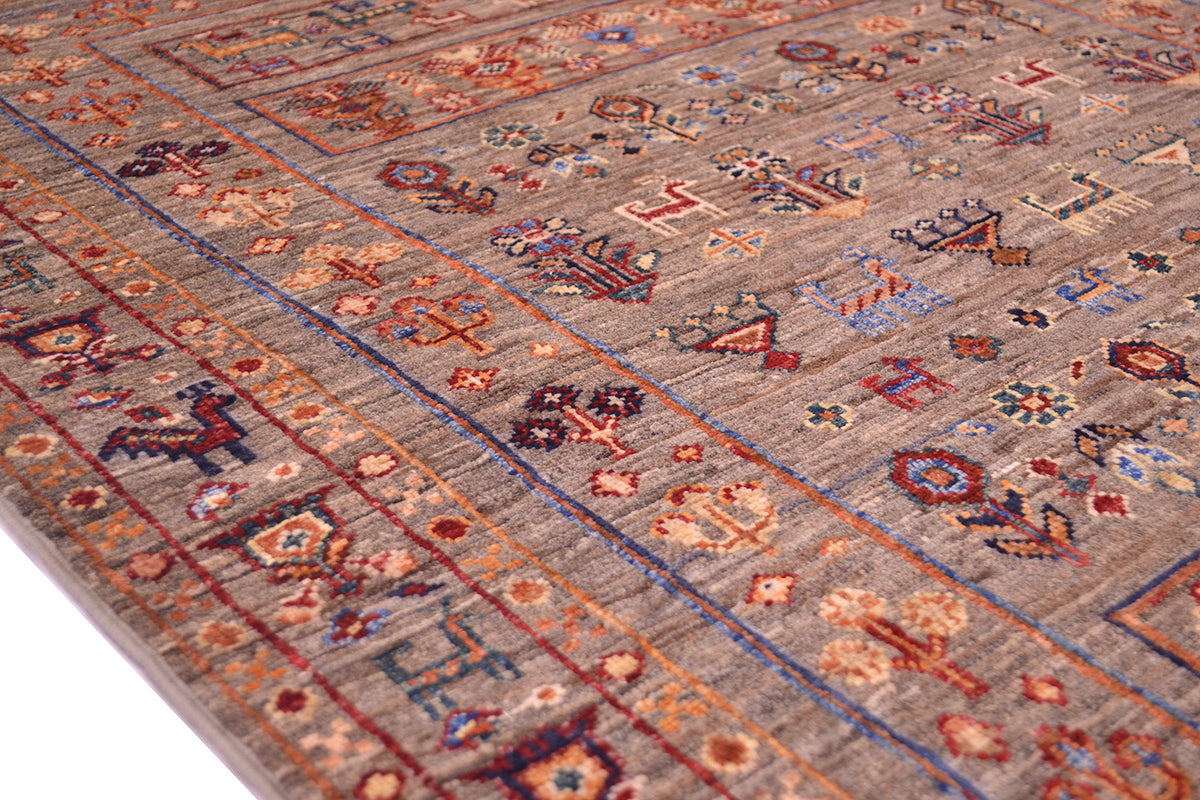 A close-up of a traditional patterned Samarkand Afghan wool rug with a warm taupe-gray base and intricate motifs in rust red, blue, beige, and brown.