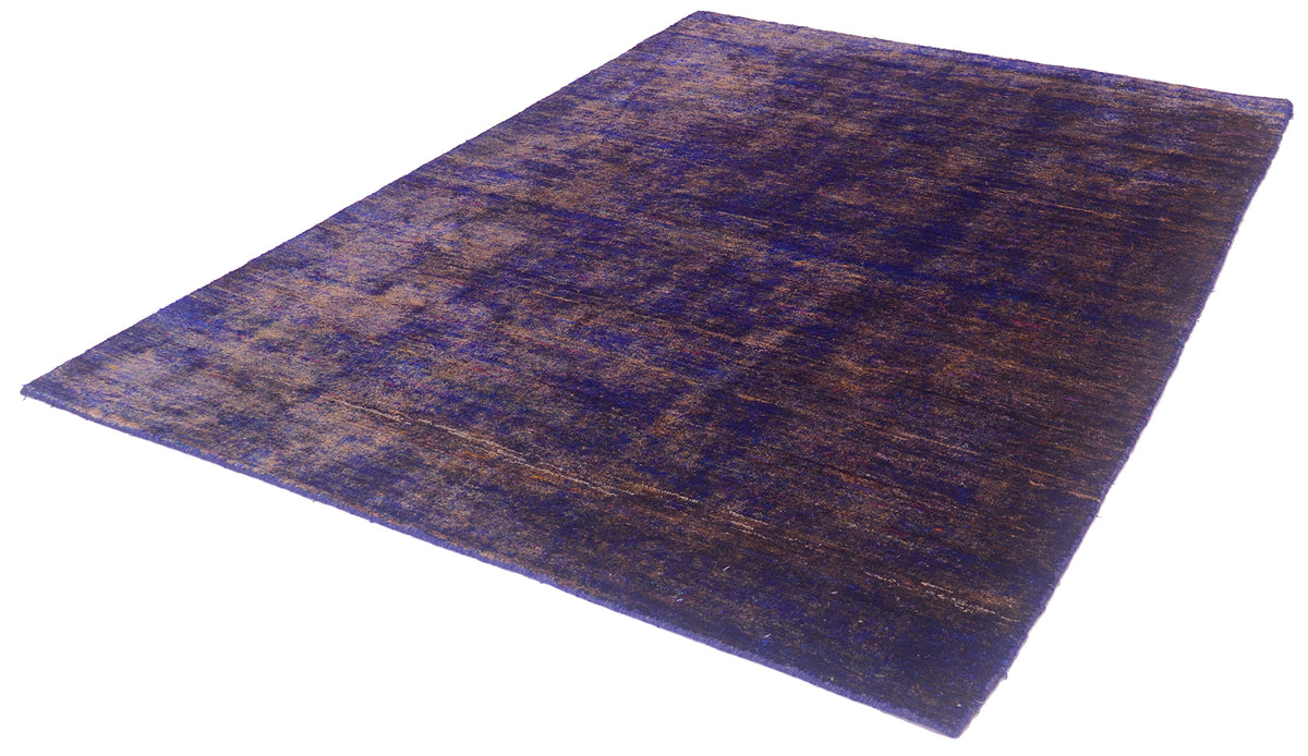 A rectangular area sari silk Indian rug with a distressed, vintage pattern in deep purple and brown tones, shown from an elevated angle on a white background.
