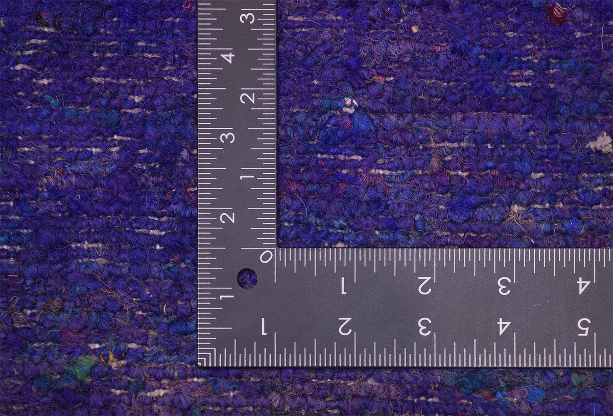 A close-up of the knotted back of a dark blue and purple handmade Indian Sari Silk rug with a metal L-square ruler placed in the corner to show scale.