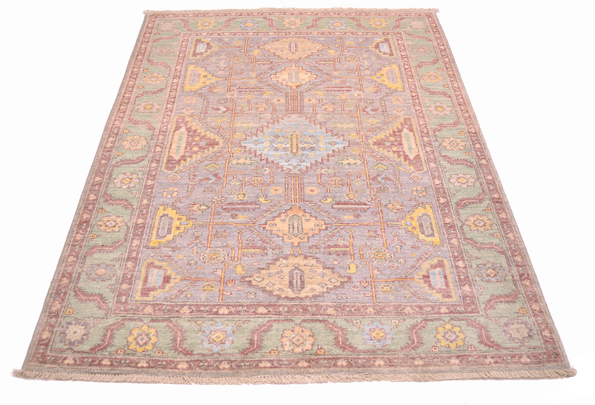 Detailed view of All over geometric design of Afghan Serapi Carpet with main field colours of light grey surrounded by a green border and soft red pink minor borders and stylized vines.