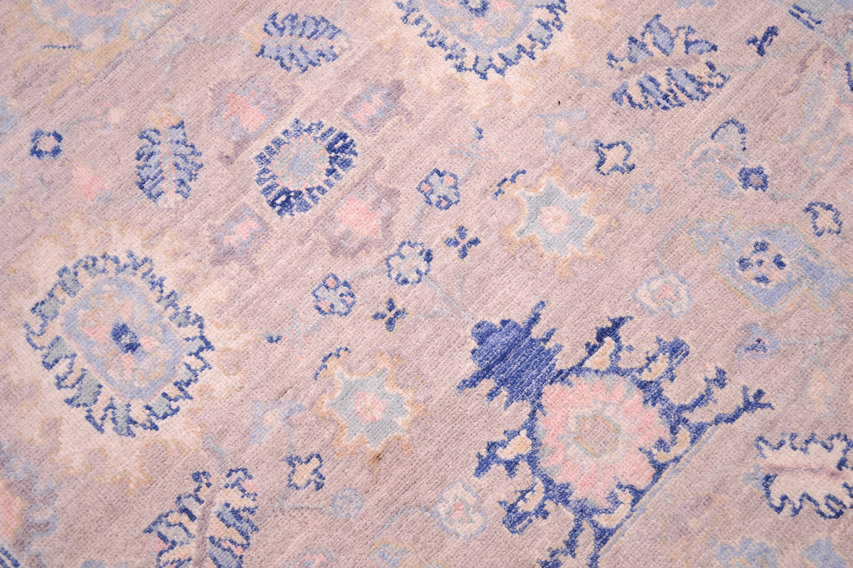 Detailed close up view of main field of afghan serapi design rug with pure wool pile. Multi-lobed flowers and palmettes flourish the the main field with cloudband border and stylized leaves in blue, grey and cream.