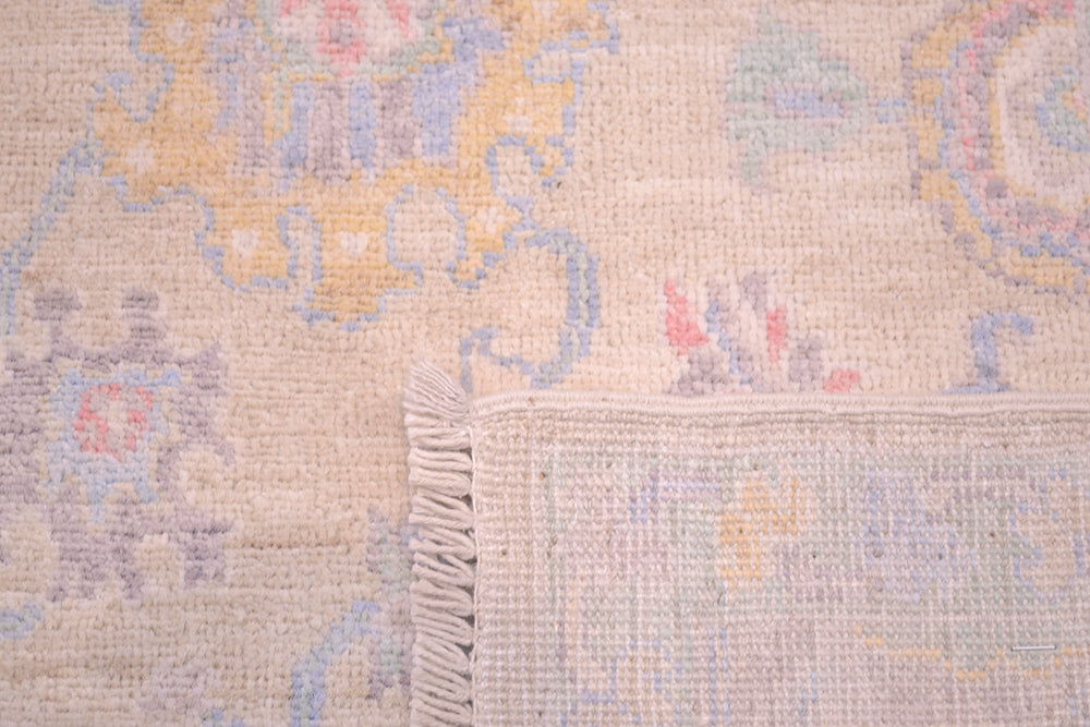 Detail of back of rug showing back of knots of handwoven rug and close up of field with delicate subtte colourways of soft hues.