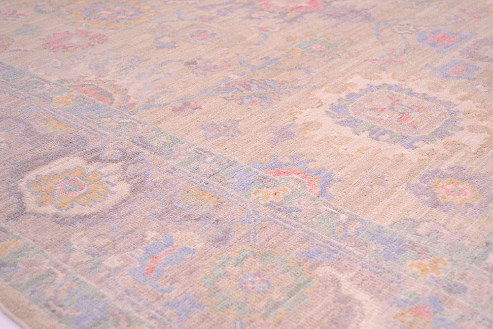 Close up image of border and field of handknotted rug with soft pleasing colours and cloudband border design with a soft grey/mauve background.