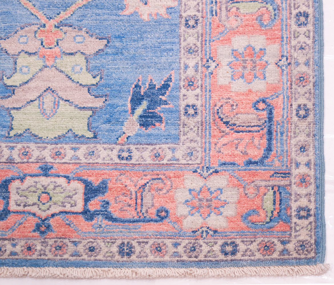 Corner detail of Afghan runner rug with traditional border and dark blue outlining and detailing. Attractive soft light sky blue field.