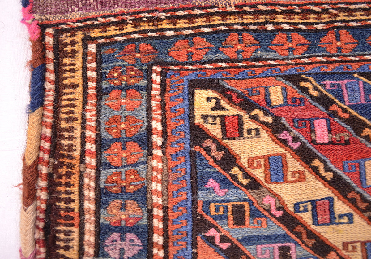 Antique khorjin rug corner close-up with diamond accents and blue rust border