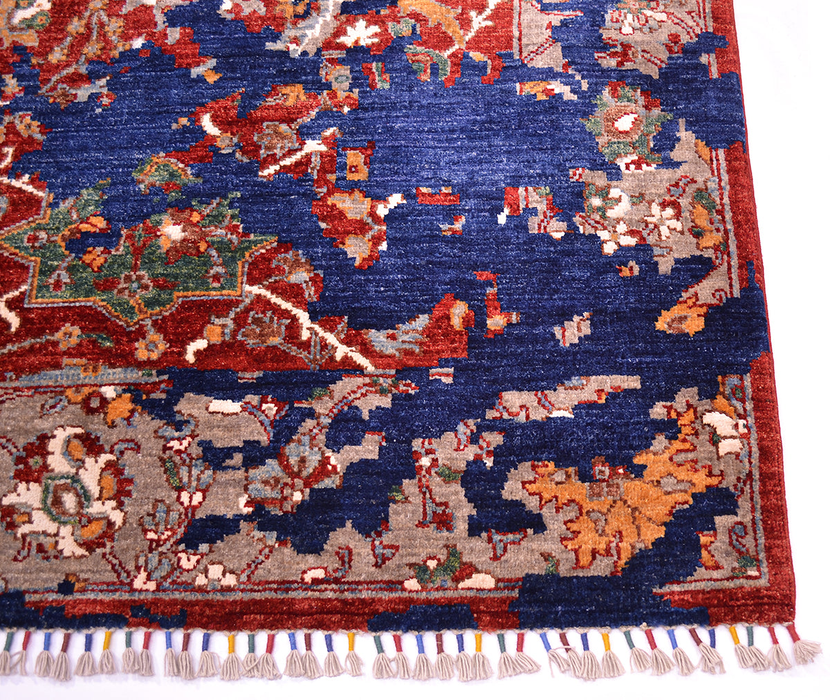 A close-up of a handmade Modern Sickle-Leaf carpet showing its detailed woven pattern, deep navy blue field, red border, and multicolored fringe.