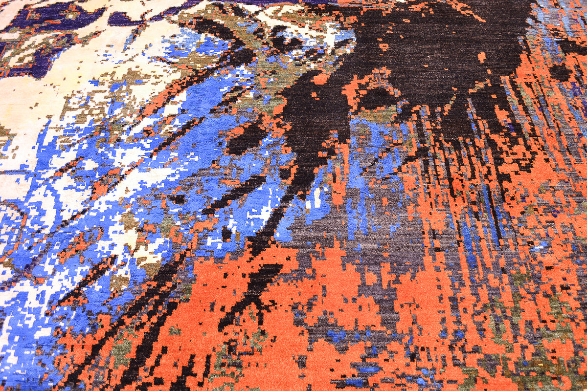 A close-up of a textured handmade carpet featuring an abstract, pixelated pattern with prominent blocks of rust orange, medium blue, black, and cream.