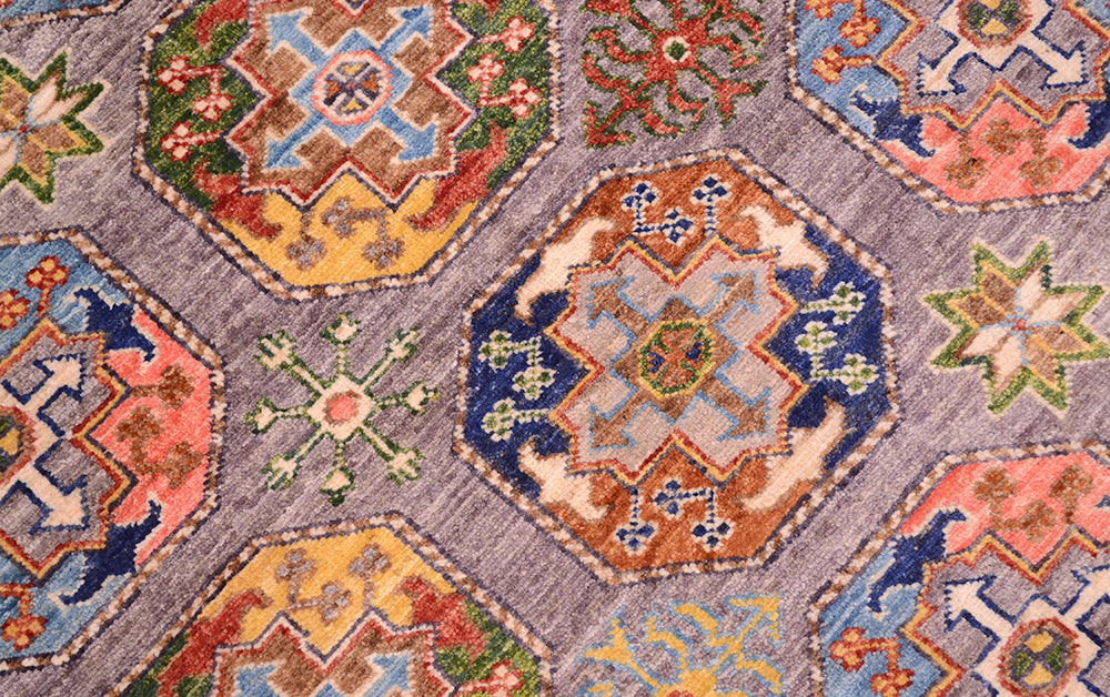 Detail view of Ersari guls of fil pai design Sultani rug with secondary guls of eight-pointed stars and starflowers. Colours of tan, rust red, coral pinks, greens, gold and blues.