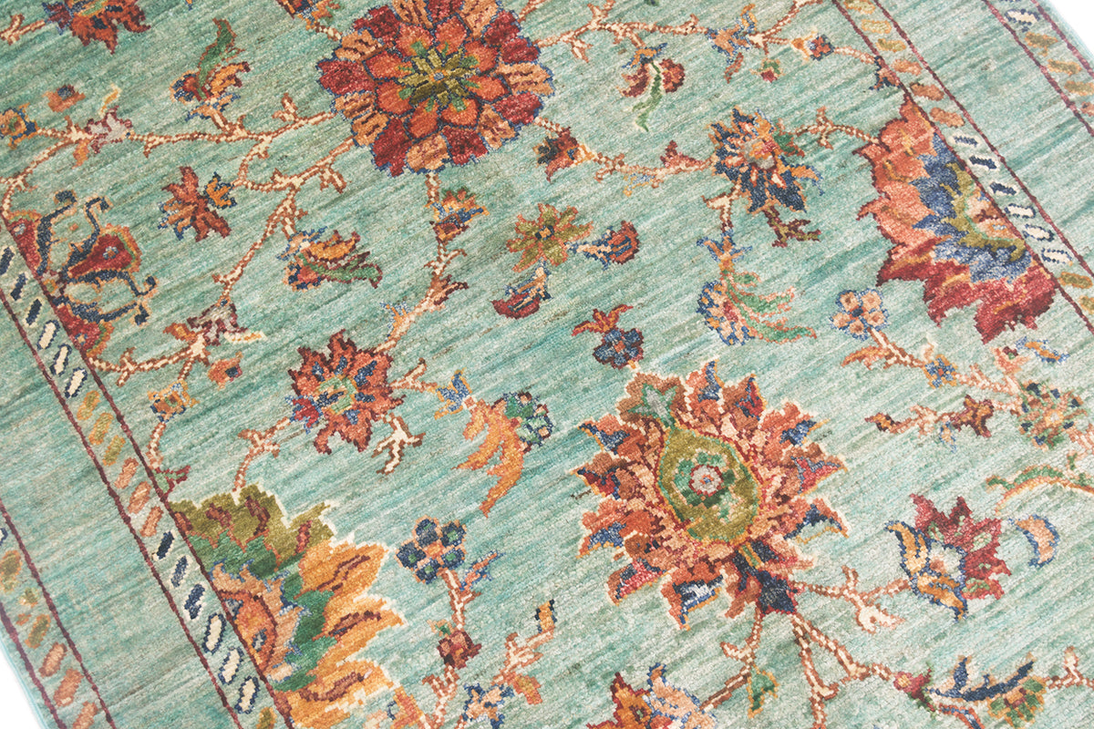 Close up detail of main field of handknotted Afghan Sultani rug with large flowerhead and palmettes. Flowinng flowers and leaves interconnected.Aqua, light turquoise field colour.