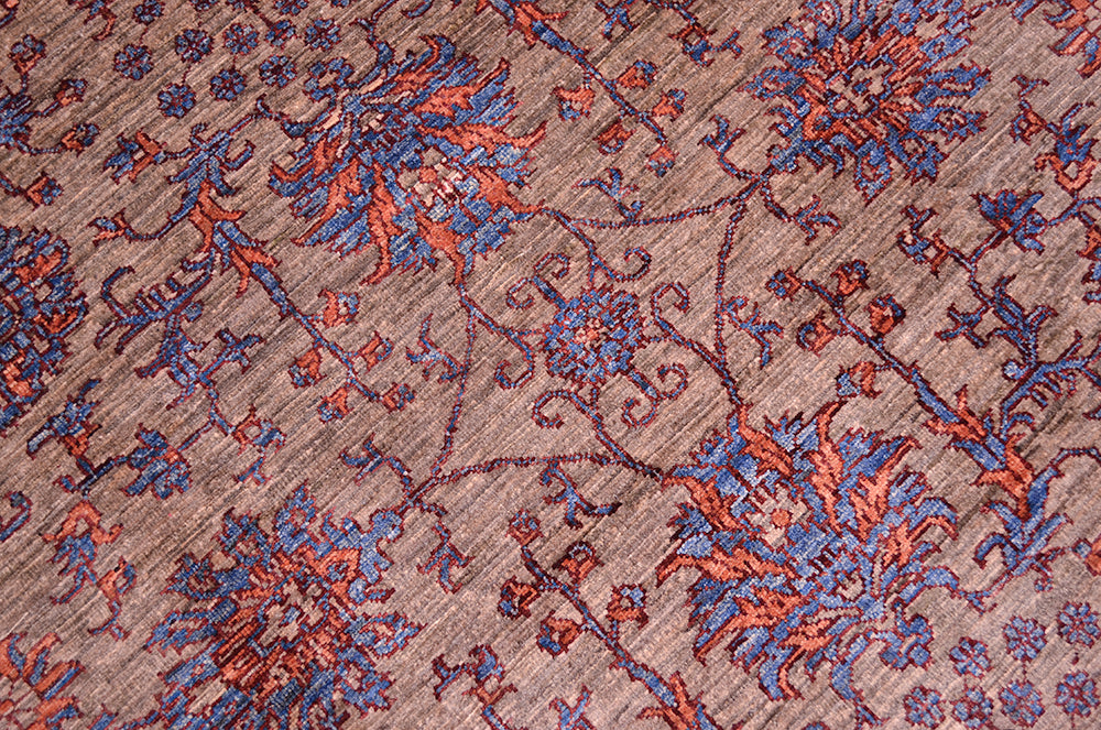 Close up detail of main field of handmade rug handknotted in Afghanistan. Natural grey ground field with blue and orange detaling.
