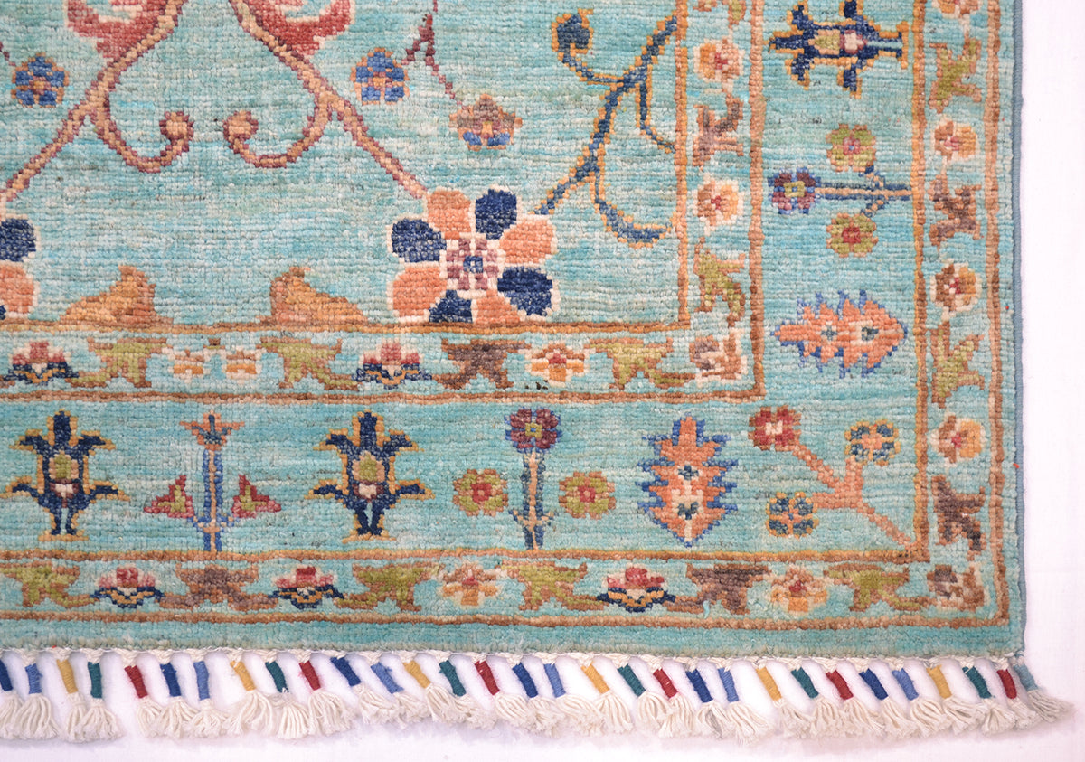 Corner detail of multicoloured handknotted rug with cotton warp fringes bound with colourful woollen yarn. Handspun pure wool pile.