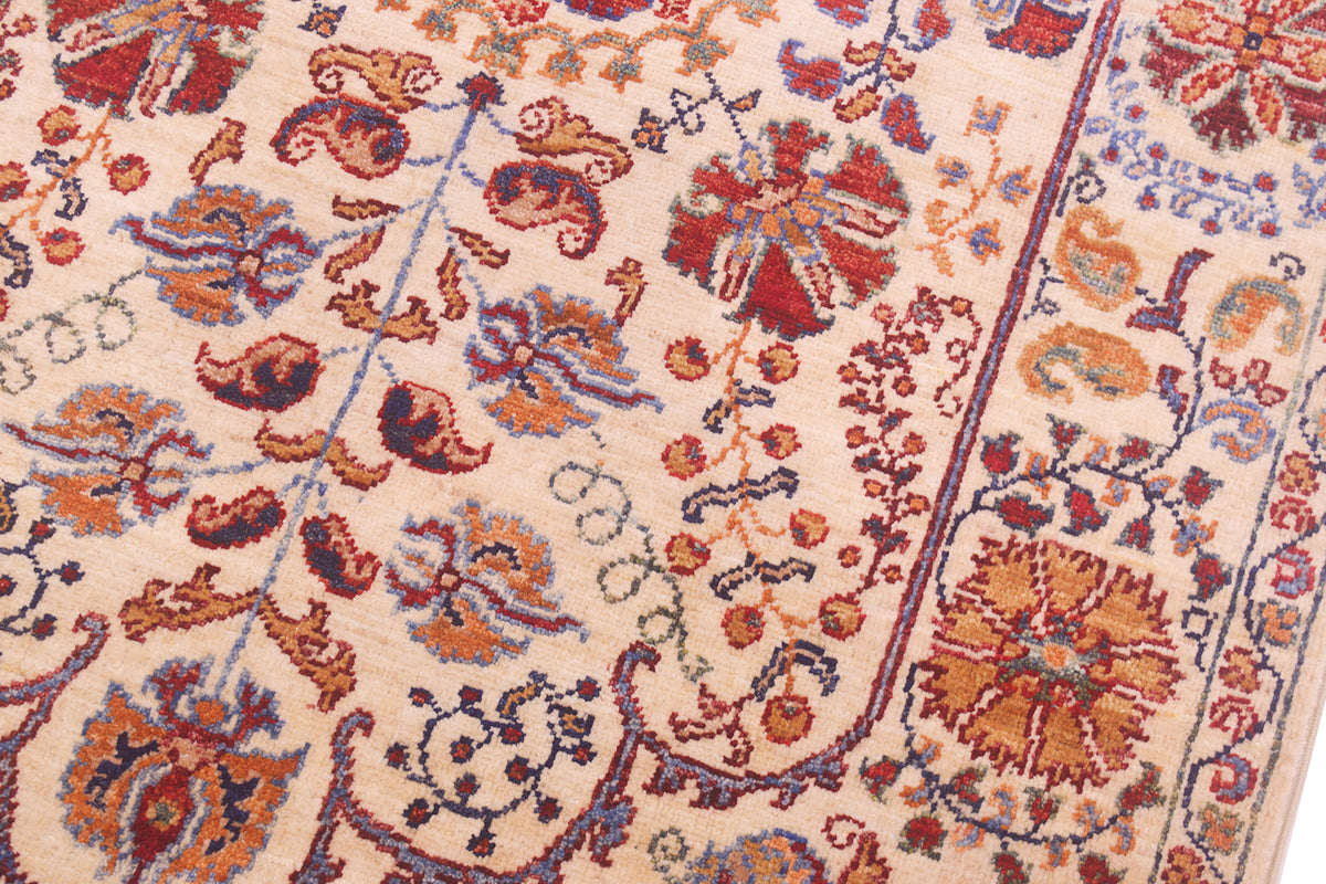 Rug close-up of floral pattern panels with red, blue and orange accents on cream