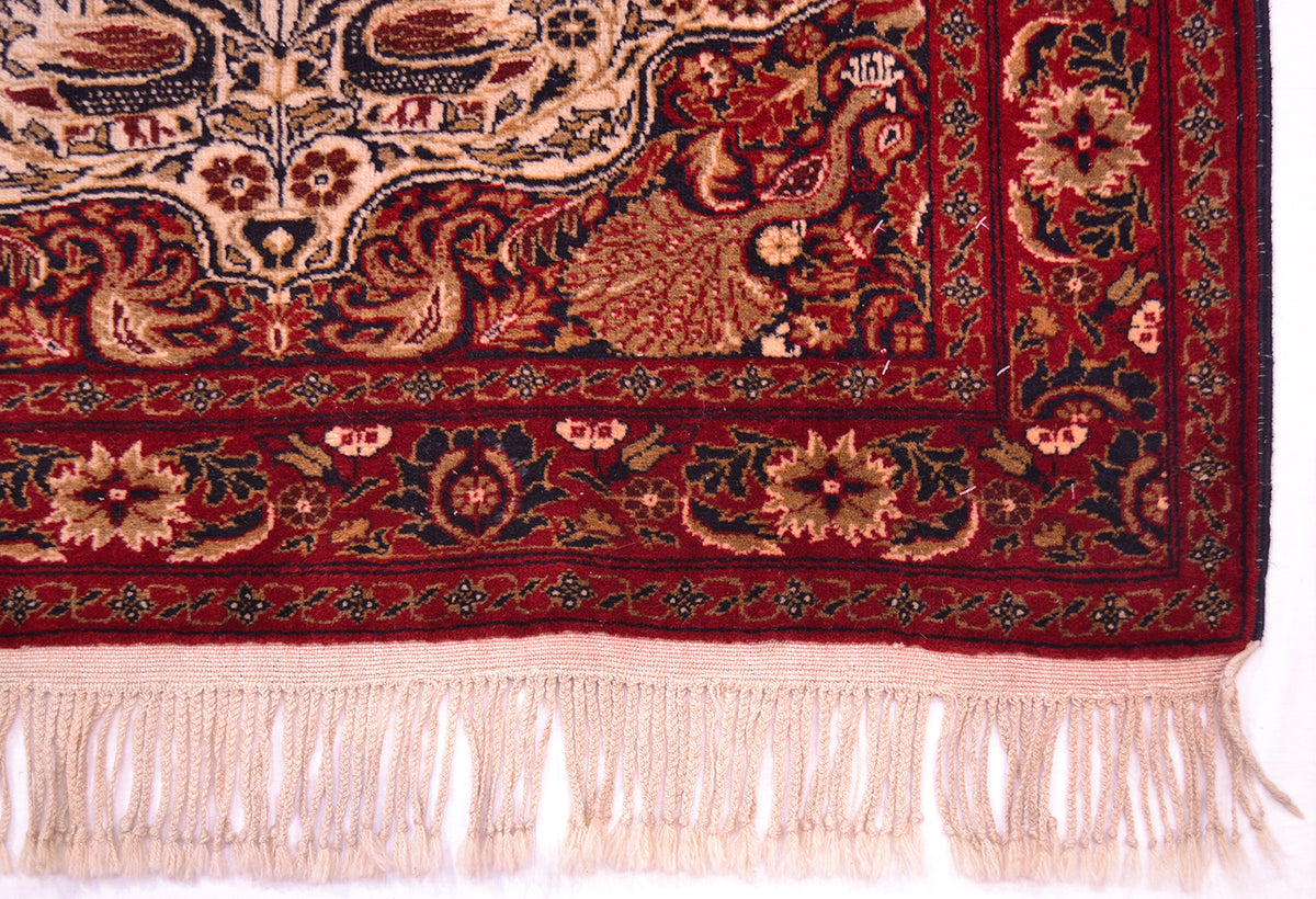 Old Belouch-Tavusi rug lower border close-up with cream motifs and light pink fringe.