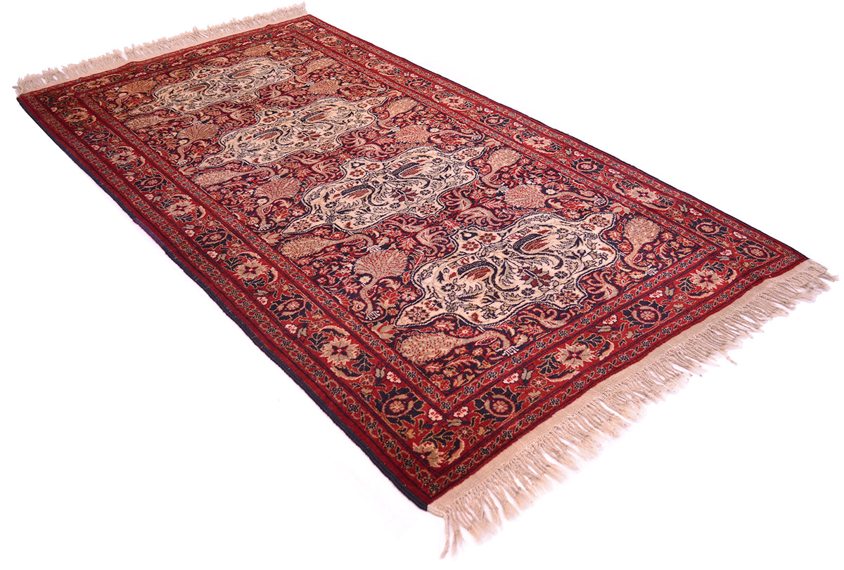 Old Belouch-Tavusi rug laid flat in red and cream with decorative border, corner tassels.
