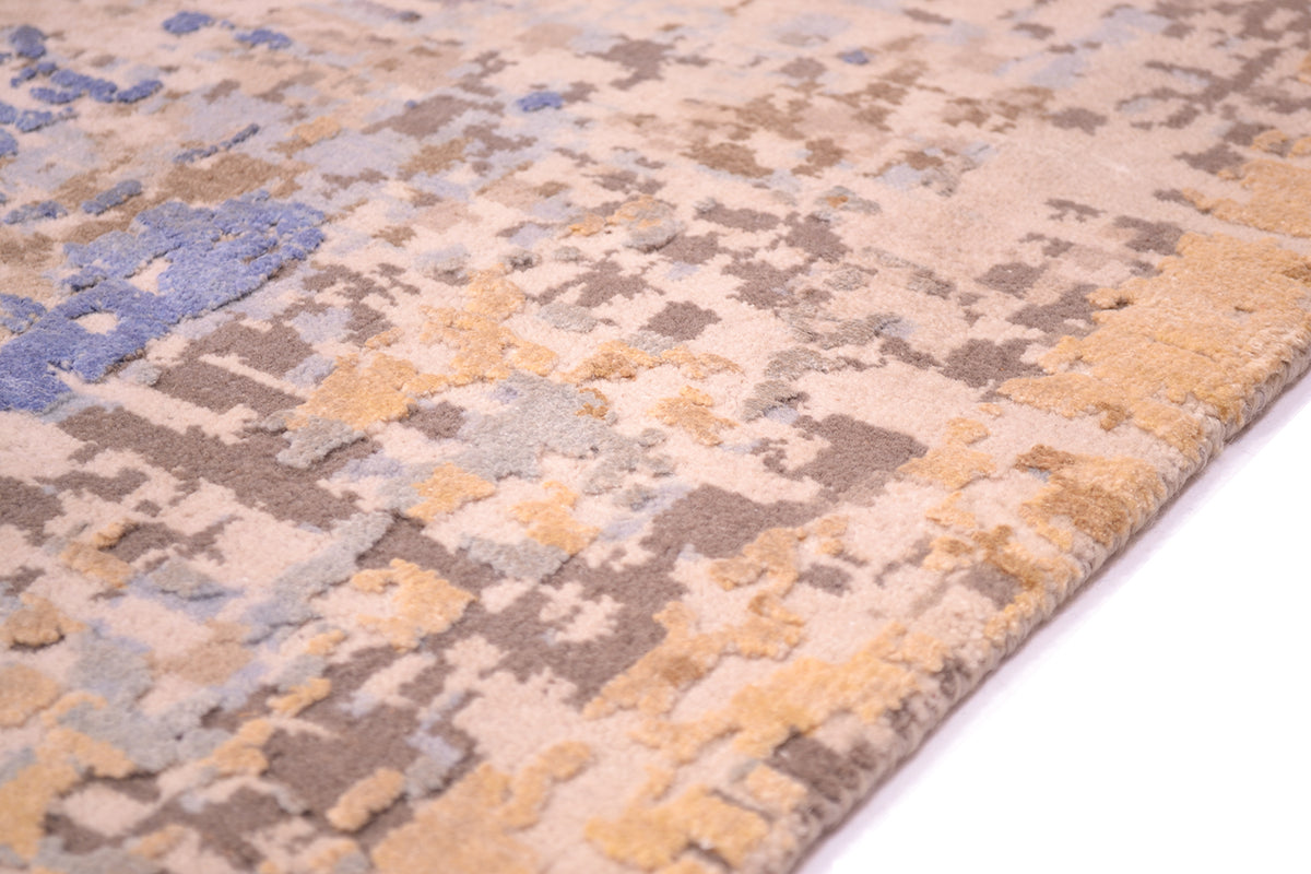 Detail of hadnknotted Indian carpet with wool and silk pile in blues, golds, greys and beiges.