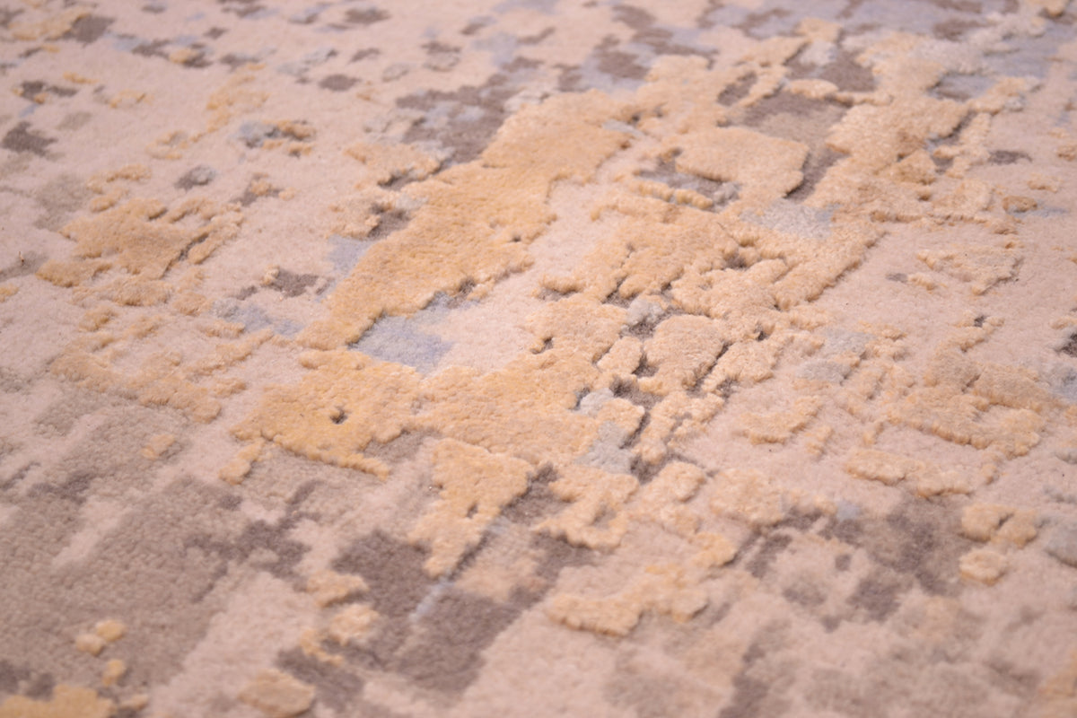 Detailed view of handknotted carpet with soft greys and beiges wool pile with raised silk highlights of golden creams and abstract textures and high low pile.